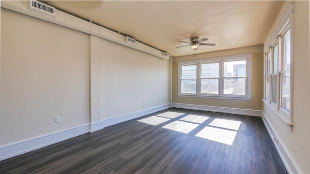 unfurnished room with visible vents, baseboards, and dark wood-style flooring