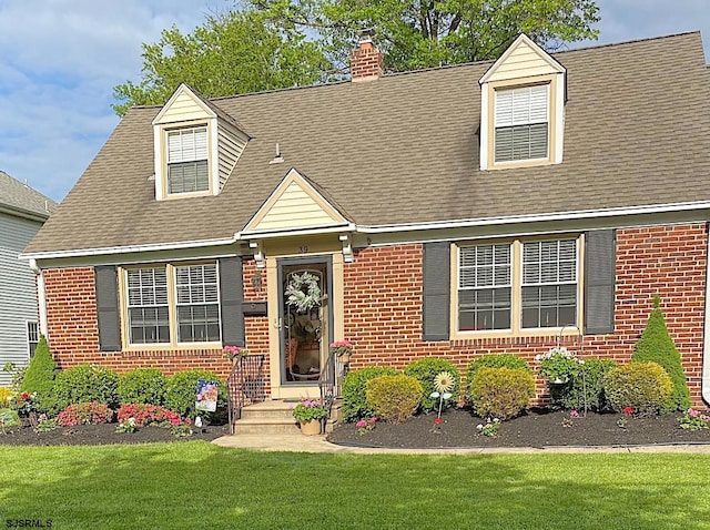 cape cod-style house with brick siding, a chimney, and a front lawn