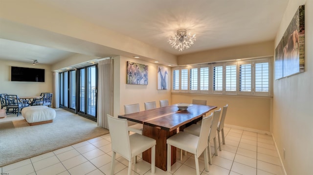 dining space featuring light tile patterned floors, a notable chandelier, light carpet, and baseboards