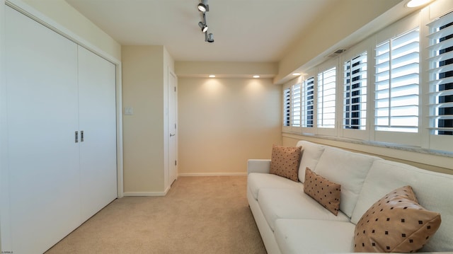 living area featuring light carpet, rail lighting, and baseboards