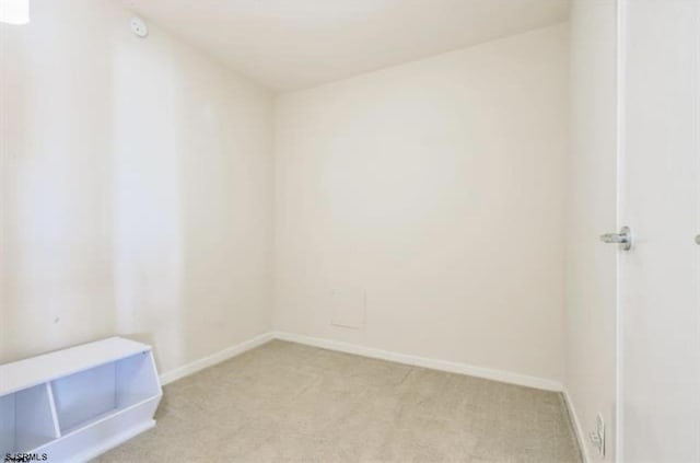 spare room with baseboards and light carpet