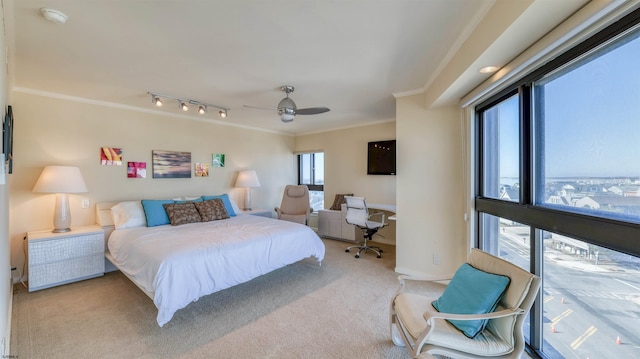 carpeted bedroom with ceiling fan, crown molding, and track lighting