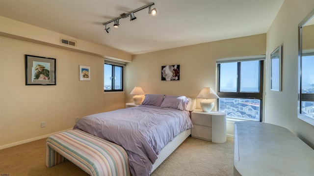 bedroom featuring visible vents, light carpet, multiple windows, and baseboards