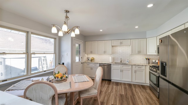 kitchen featuring tasteful backsplash, white cabinets, stainless steel appliances, and wood finished floors