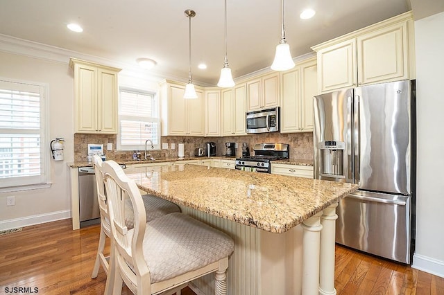 kitchen featuring tasteful backsplash, crown molding, dark wood-type flooring, appliances with stainless steel finishes, and cream cabinets