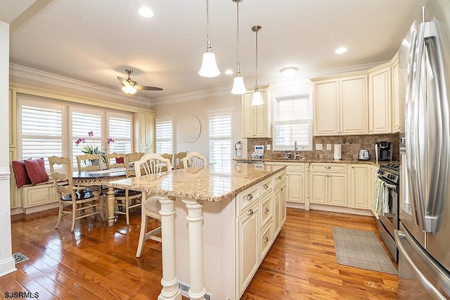 kitchen with a breakfast bar, stainless steel appliances, crown molding, and light wood-style floors