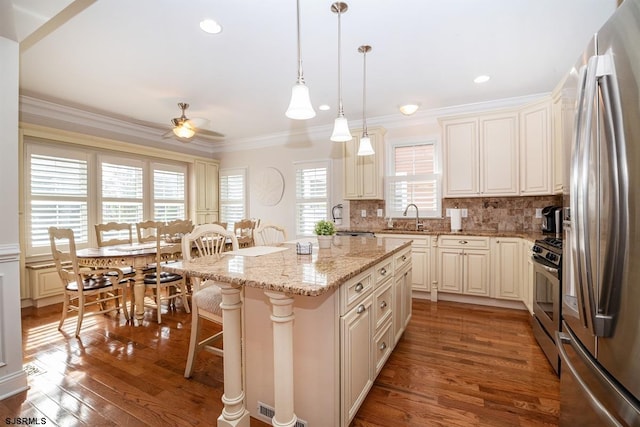 kitchen with crown molding, appliances with stainless steel finishes, a kitchen breakfast bar, wood finished floors, and a sink