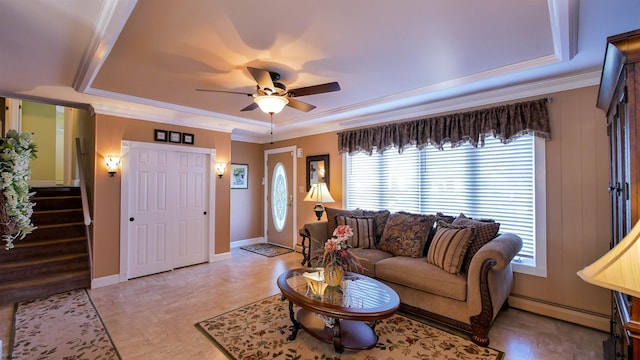 living room featuring a baseboard radiator, a ceiling fan, crown molding, and stairway