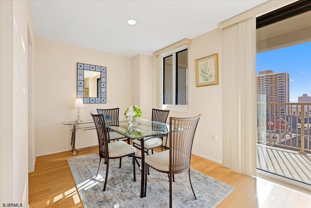 dining area with baseboards, a city view, and wood finished floors