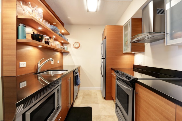 kitchen featuring brown cabinets, stainless steel appliances, modern cabinets, wall chimney exhaust hood, and a sink