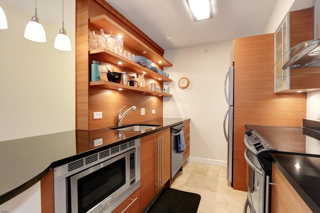 kitchen with dark countertops, appliances with stainless steel finishes, modern cabinets, wall chimney exhaust hood, and a sink