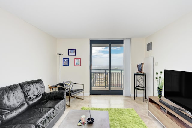 living room with visible vents, a wall of windows, and baseboards