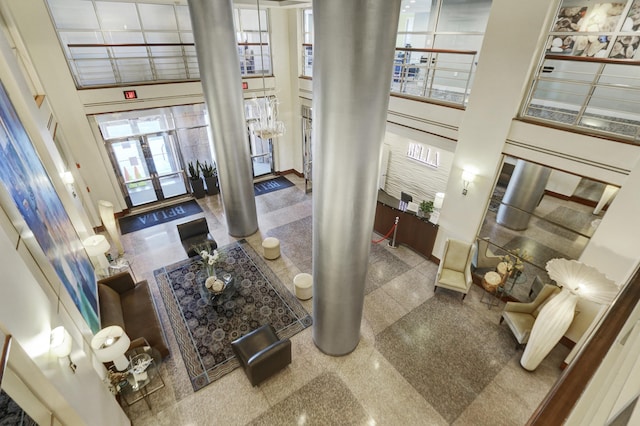 foyer with granite finish floor, a high ceiling, and decorative columns