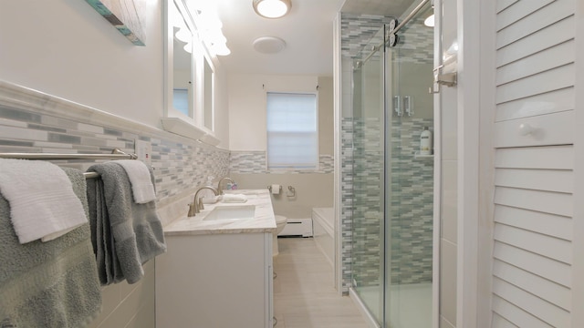 bathroom with backsplash, a stall shower, wood finished floors, vanity, and a baseboard radiator