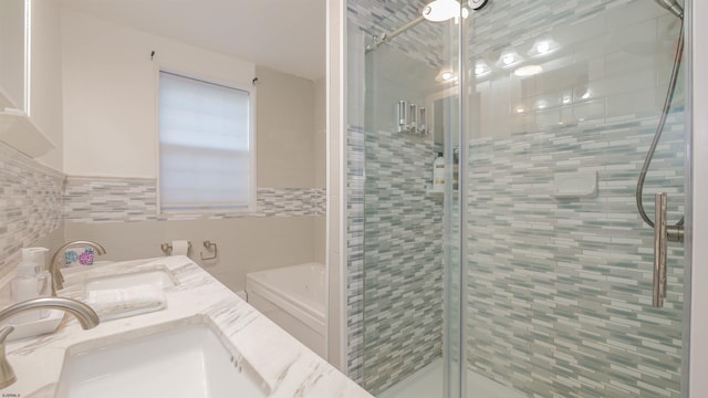 full bath with a sink, tile walls, a stall shower, and a tub