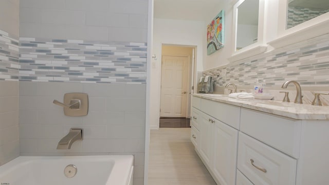 bathroom with a sink, a bathing tub, tile walls, and double vanity