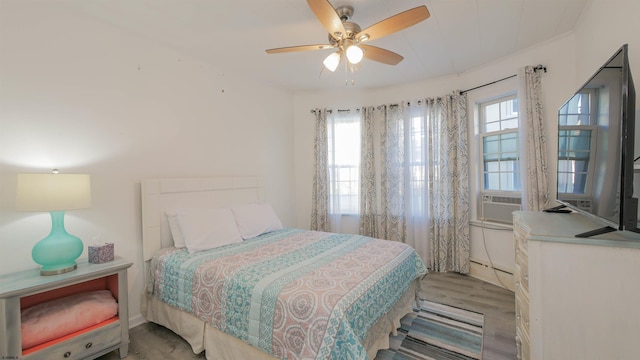 bedroom featuring cooling unit, wood finished floors, baseboard heating, and ceiling fan