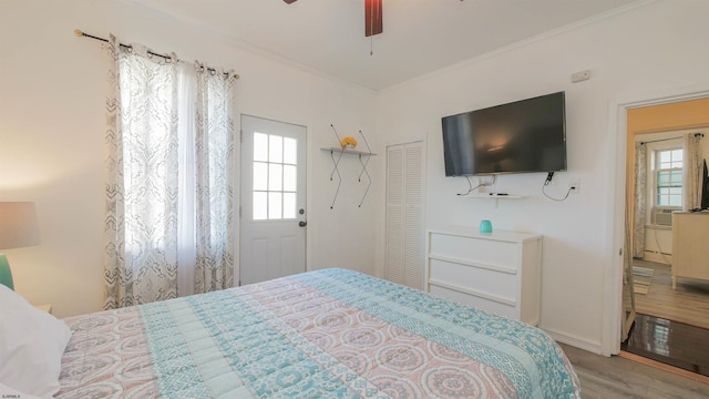 bedroom with a closet, multiple windows, wood finished floors, and crown molding