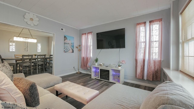 living room featuring a wealth of natural light, crown molding, and wood finished floors