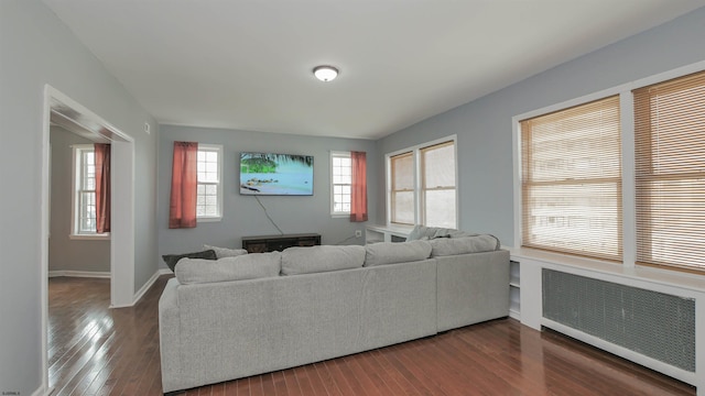 living room with radiator heating unit, baseboards, and dark wood-style flooring