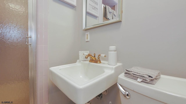 bathroom featuring a stall shower, toilet, and a sink