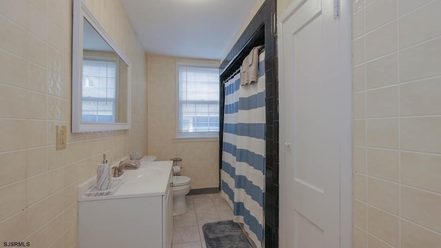 full bath with curtained shower, tile walls, toilet, tile patterned floors, and vanity