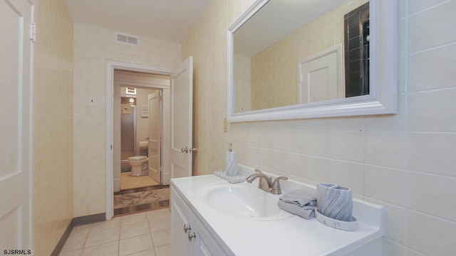 bathroom featuring tile patterned flooring, tile walls, toilet, and visible vents