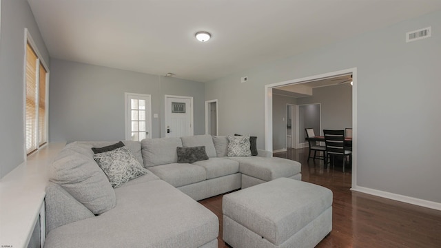 living area with dark wood-style floors, visible vents, and baseboards