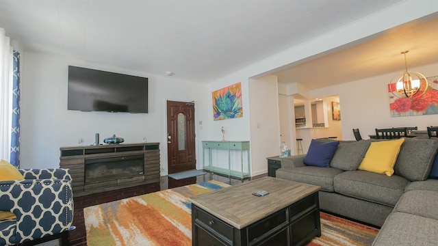 living room featuring a glass covered fireplace, an inviting chandelier, and wood finished floors