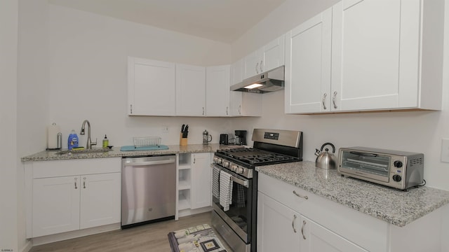 kitchen with under cabinet range hood, white cabinets, appliances with stainless steel finishes, and a sink