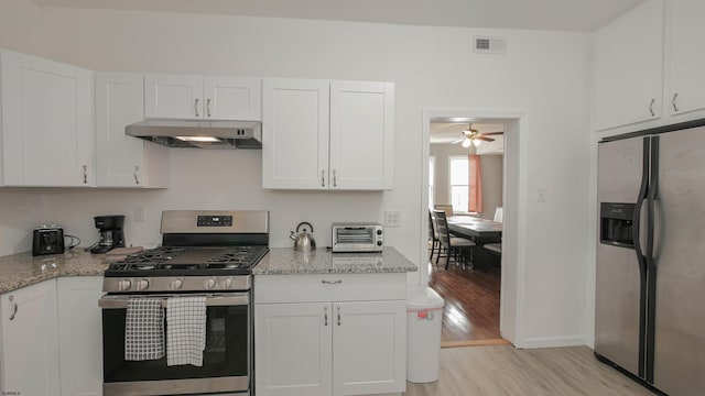 kitchen featuring visible vents, light wood finished floors, stainless steel appliances, under cabinet range hood, and white cabinetry