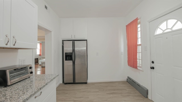 kitchen featuring a baseboard heating unit, a toaster, light wood-type flooring, stainless steel fridge, and white cabinetry