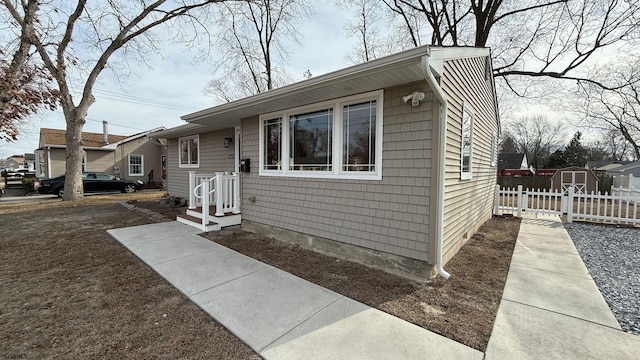 bungalow-style home featuring an outdoor structure, fence, and a shed