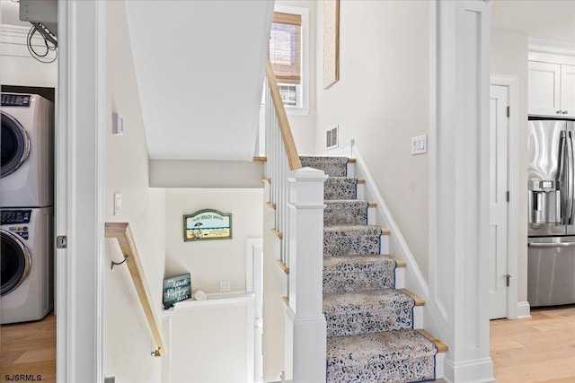 staircase featuring visible vents, wood finished floors, and stacked washer and clothes dryer