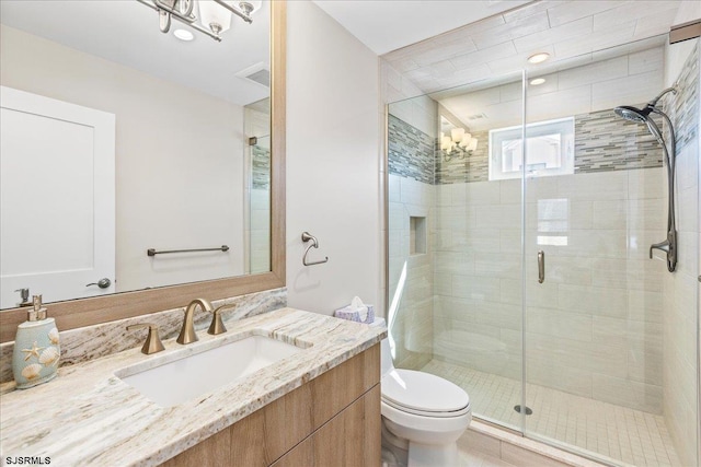 bathroom featuring vanity, toilet, visible vents, and a stall shower