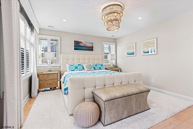 bedroom featuring light wood finished floors, a notable chandelier, recessed lighting, and baseboards