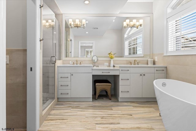 bathroom featuring a soaking tub, tile walls, two vanities, and a shower stall