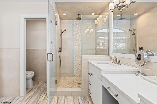 full bathroom with toilet, wood finished floors, tile walls, a shower stall, and vanity