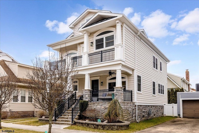 view of front facade featuring ceiling fan, a porch, an outdoor structure, and a balcony