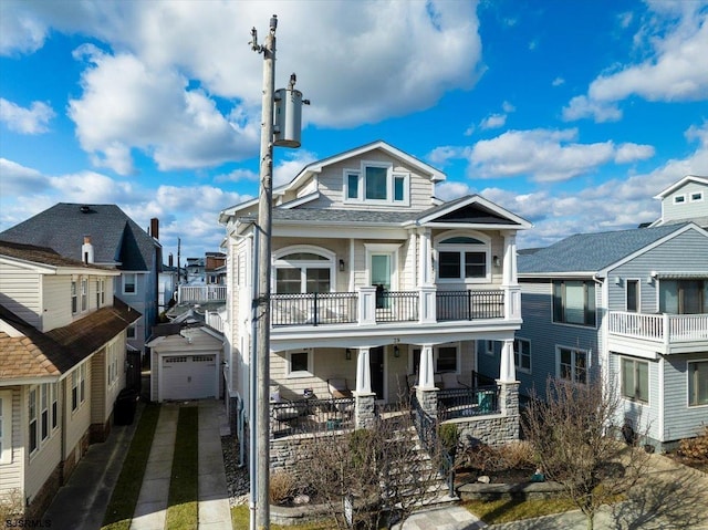 view of front of house featuring a detached garage, a residential view, a porch, a balcony, and driveway