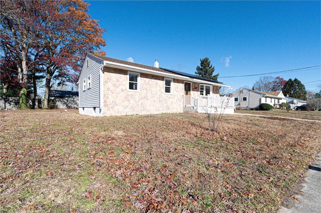 view of front facade featuring solar panels, a front yard, and stone siding