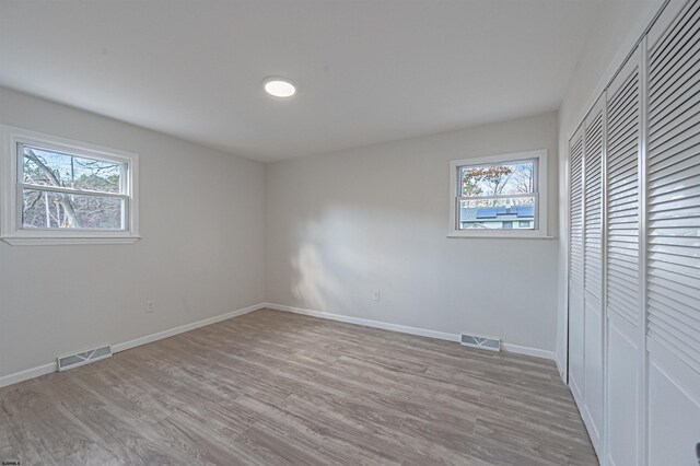 unfurnished bedroom featuring visible vents, multiple windows, and light wood-type flooring