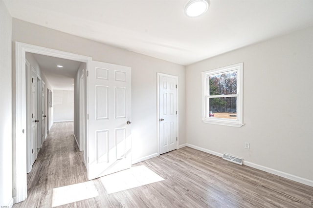 unfurnished bedroom featuring wood finished floors, visible vents, and baseboards