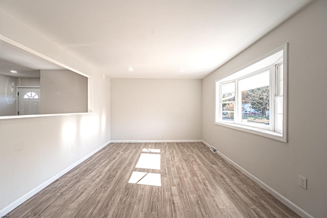 unfurnished room with visible vents, baseboards, a healthy amount of sunlight, and wood finished floors