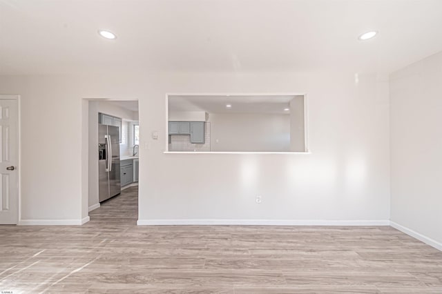 spare room with light wood-style floors, recessed lighting, baseboards, and a sink