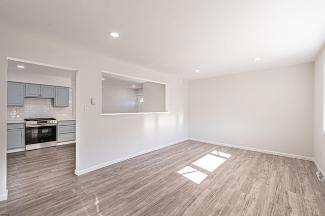 unfurnished living room featuring recessed lighting, light wood-type flooring, and baseboards