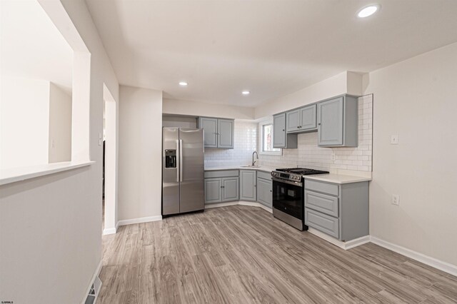 kitchen featuring tasteful backsplash, appliances with stainless steel finishes, light wood-type flooring, and gray cabinetry