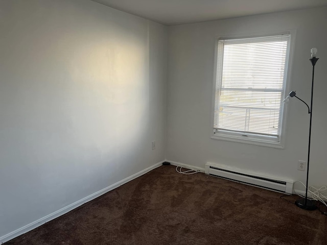 spare room with baseboards, dark colored carpet, and a baseboard radiator