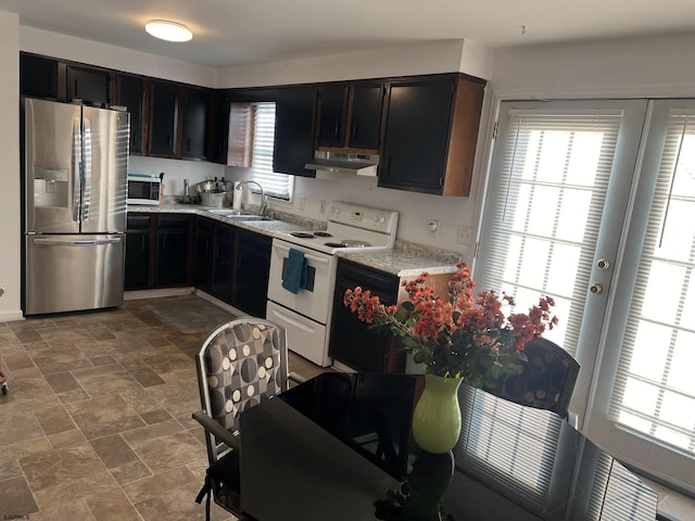 kitchen featuring under cabinet range hood, stone finish flooring, a sink, stainless steel appliances, and light countertops