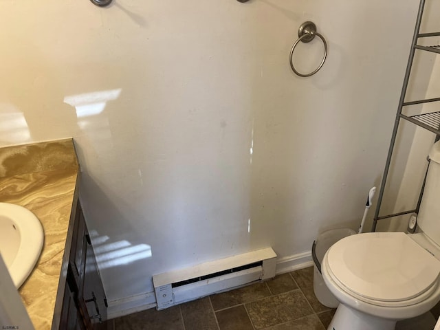 bathroom featuring vanity, toilet, a baseboard heating unit, and baseboards